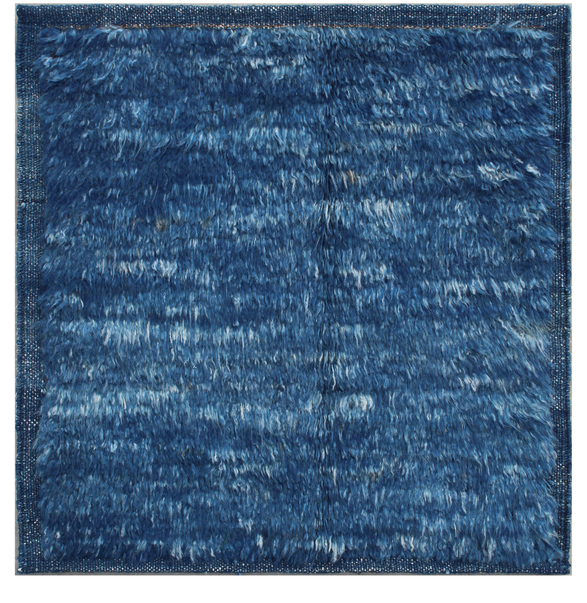 A square blue shag rug with a textured, fluffy pile and a subtle woven border, shown flat against a white background. Atlantica Organics curates antique and handmade rugs, Persian, Afghan, Tibetan, Pakistani, Turkish Oushak, Kilim, Khotan, tribal and contemporary textiles for luxury interiors, homes and real estate. Our collections connect timeless craftsmanship with interior design, furniture, fine art, architecture and modern living. Explore curated rugs, collectible textiles, natural materials, cultural