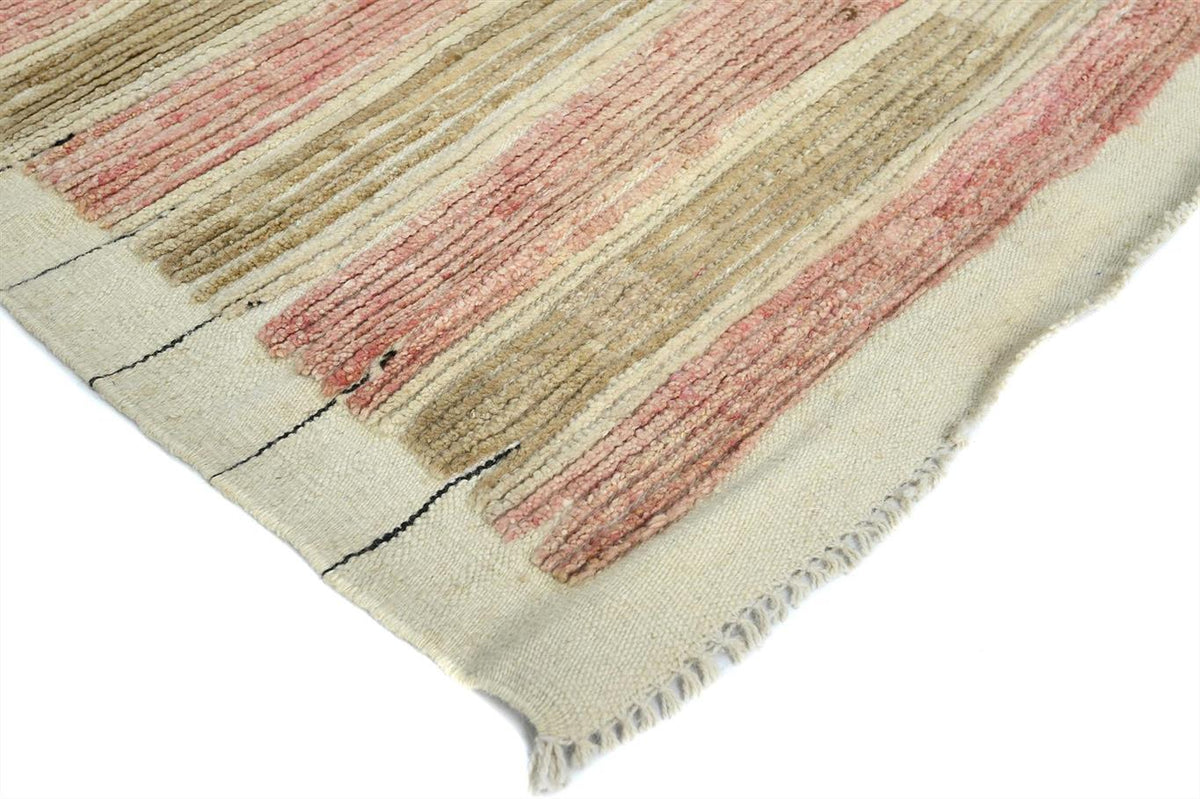 A close-up of a woven rug corner showing a cream base with vertical stripes in dusty pink and tan, finished with a frayed edge. Atlantica Organics curates antique and handmade rugs, Persian, Afghan, Tibetan, Pakistani, Turkish Oushak, Kilim, Khotan, tribal and contemporary textiles for luxury interiors, homes and real estate. Our collections connect timeless craftsmanship with interior design, furniture, fine art, architecture and modern living. Explore curated rugs, collectible textiles, natural materials,