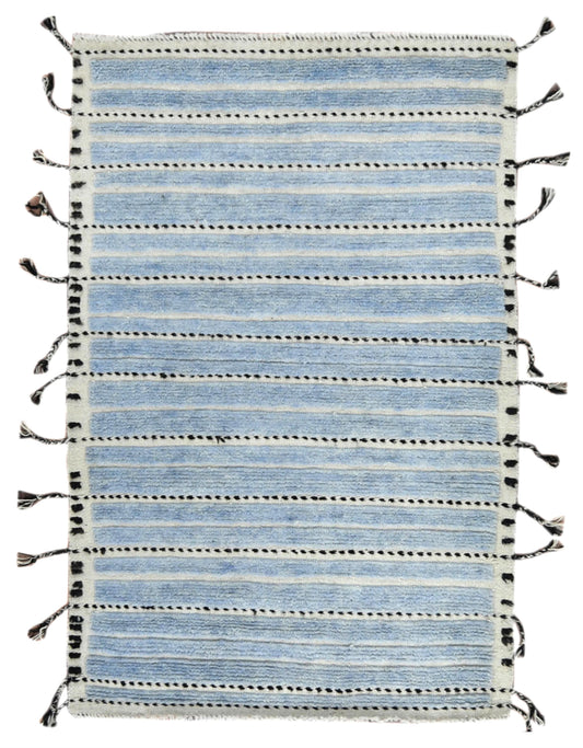 A rectangular woven rug with horizontal light blue and off-white stripes, accented by thin black dotted lines and black tassels along the sides, shown flat against a white background.Atlantica Organics curates antique and handmade rugs, Persian, Afghan, Tibetan, Pakistani, Turkish Oushak, Kilim, Khotan, tribal and contemporary textiles for luxury interiors, homes and real estate. Our collections connect timeless craftsmanship with interior design, furniture, fine art, architecture and modern living. Explore