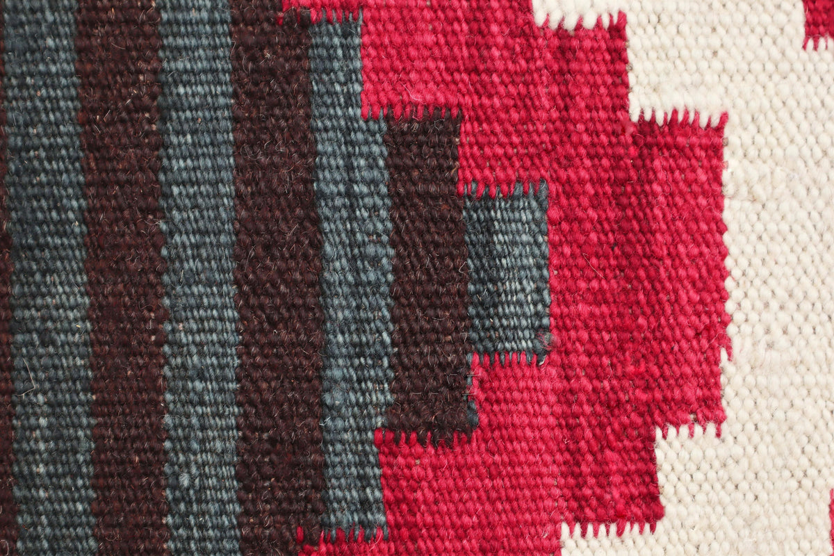 Close-up of a woven textile pattern with vertical dark brown and gray stripes on the left and bold red geometric blocks on the right, set against a cream woven background.Atlantica Organics curates antique and handmade rugs, Persian, Afghan, Tibetan, Pakistani, Turkish Oushak, Kilim, Khotan, tribal and contemporary textiles for luxury interiors, homes and real estate. Our collections connect timeless craftsmanship with interior design, furniture, fine art, architecture and modern living. Explore curated rug