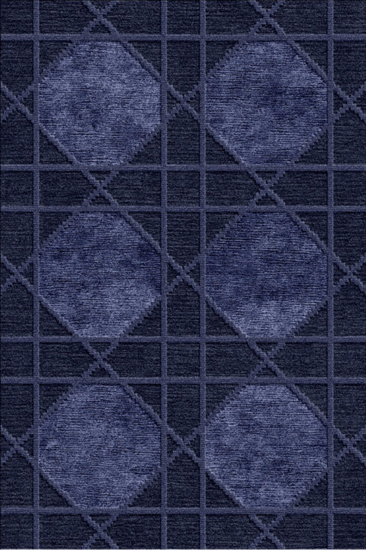 A close-up of a textured fabric or carpet pattern featuring four large diamond motifs in a medium blue-gray tone set against a dark navy grid background.Atlantica Organics curates antique and handmade rugs, Persian, Afghan, Tibetan, Pakistani, Turkish Oushak, Kilim, Khotan, tribal and contemporary textiles for luxury interiors, homes and real estate. Our collections connect timeless craftsmanship with interior design, furniture, fine art, architecture and modern living. Explore curated rugs, collectible tex
