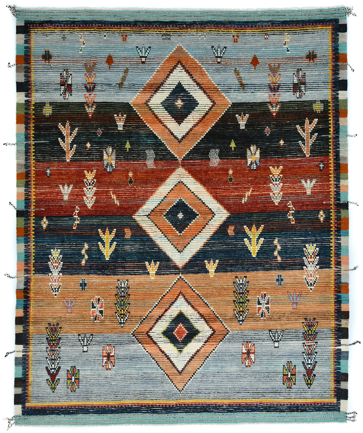 A square woven rug with a Southwestern geometric pattern, featuring three large central diamond motifs and smaller decorative elements. The color palette includes slate blue, terracotta red, rust orange, dark charcoal, cream, and turquoise. Atlantica Organics curates antique and handmade rugs, Persian, Afghan, Tibetan, Pakistani, Turkish Oushak, Kilim, Khotan, tribal and contemporary textiles for luxury interiors, homes and real estate. Our collections connect timeless craftsmanship with interior design, fu