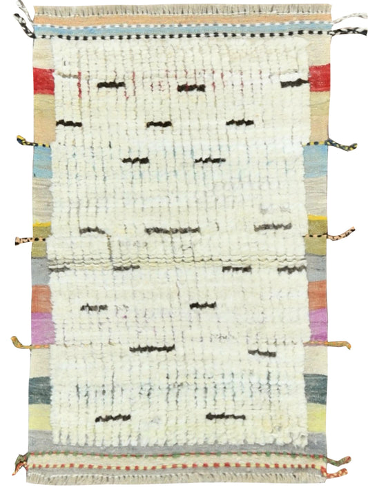 A rectangular handwoven rug with a distressed off-white center, black dash-like motifs, and multicolored striped borders in beige, blue, red, yellow, green, and purple. Atlantica Organics curates antique and handmade rugs, Persian, Afghan, Tibetan, Pakistani, Turkish Oushak, Kilim, Khotan, tribal and contemporary textiles for luxury interiors, homes and real estate. Our collections connect timeless craftsmanship with interior design, furniture, fine art, architecture and modern living. Explore curated rugs,