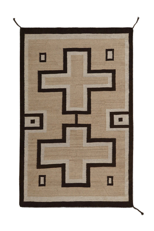 A rectangular woven rug with a Southwestern geometric design, featuring two large stepped cross motifs and small square accents in beige, brown, and off-white, set against a solid black background. Atlantica Organics curates antique and handmade rugs, Persian, Afghan, Tibetan, Pakistani, Turkish Oushak, Kilim, Khotan, tribal and contemporary textiles for luxury interiors, homes and real estate. Our collections connect timeless craftsmanship with interior design, furniture, fine art, architecture and modern 
