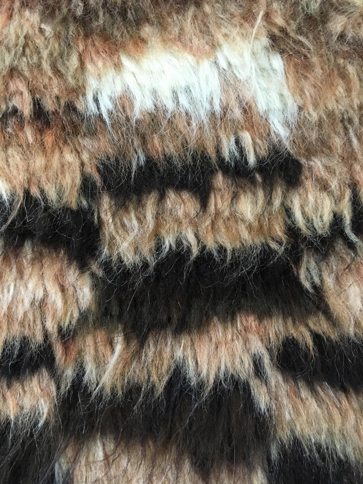 A close-up of a faux fur fabric with a leopard print pattern featuring black, brown, beige, and white tones. Atlantica Organics curates antique and handmade rugs, Persian, Afghan, Tibetan, Pakistani, Turkish Oushak, Kilim, Khotan, tribal and contemporary textiles for luxury interiors, homes and real estate. Our collections connect timeless craftsmanship with interior design, furniture, fine art, architecture and modern living. Explore curated rugs, collectible textiles, natural materials, cultural heritage,