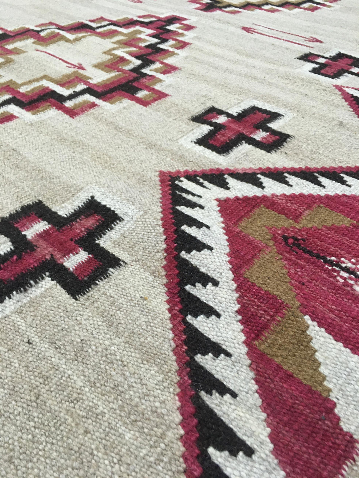 Close-up of a woven rug with a Southwestern geometric pattern in cream, red, black, and tan. Atlantica Organics curates antique and handmade rugs, Persian, Afghan, Tibetan, Pakistani, Turkish Oushak, Kilim, Khotan, tribal and contemporary textiles for luxury interiors, homes and real estate. Our collections connect timeless craftsmanship with interior design, furniture, fine art, architecture and modern living. Explore curated rugs, collectible textiles, natural materials, cultural heritage, sustainable des