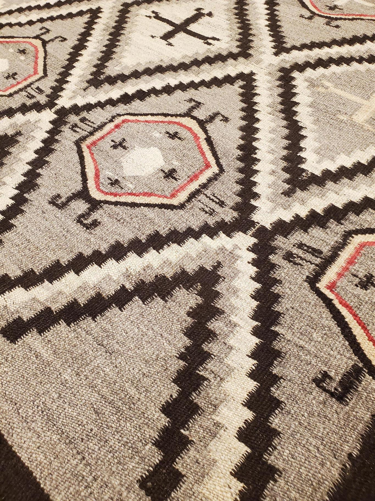 Close-up of a patterned rug with geometric designAtlantica Organics curates antique and handmade rugs, Persian, Afghan, Tibetan, Pakistani, Turkish Oushak, Kilim, Khotan, tribal and contemporary textiles for luxury interiors, homes and real estate. Our collections connect timeless craftsmanship with interior design, furniture, fine art, architecture and modern living. Explore curated rugs, collectible textiles, natural materials, cultural heritage, sustainable design and distinctive spaces for homeowners, c