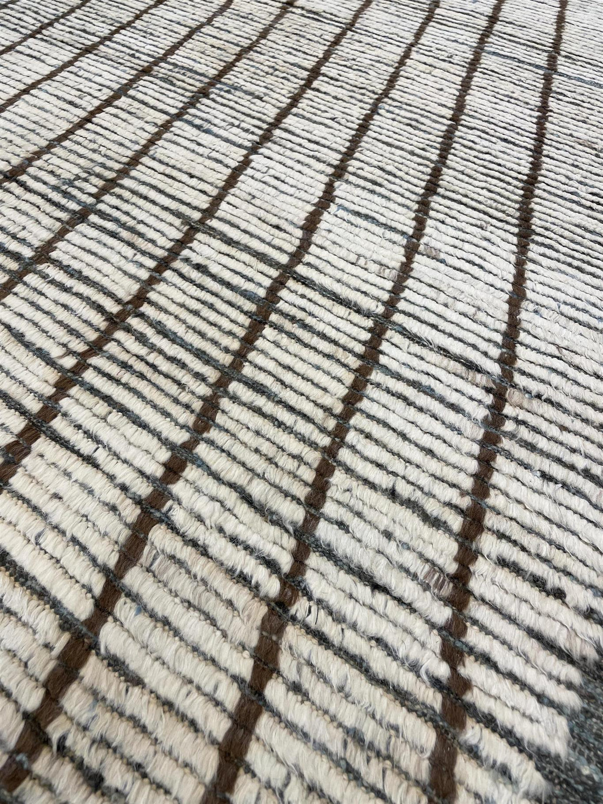 Close-up of a woven textile surface with a cream base and repeating dark brown vertical stripe pattern.