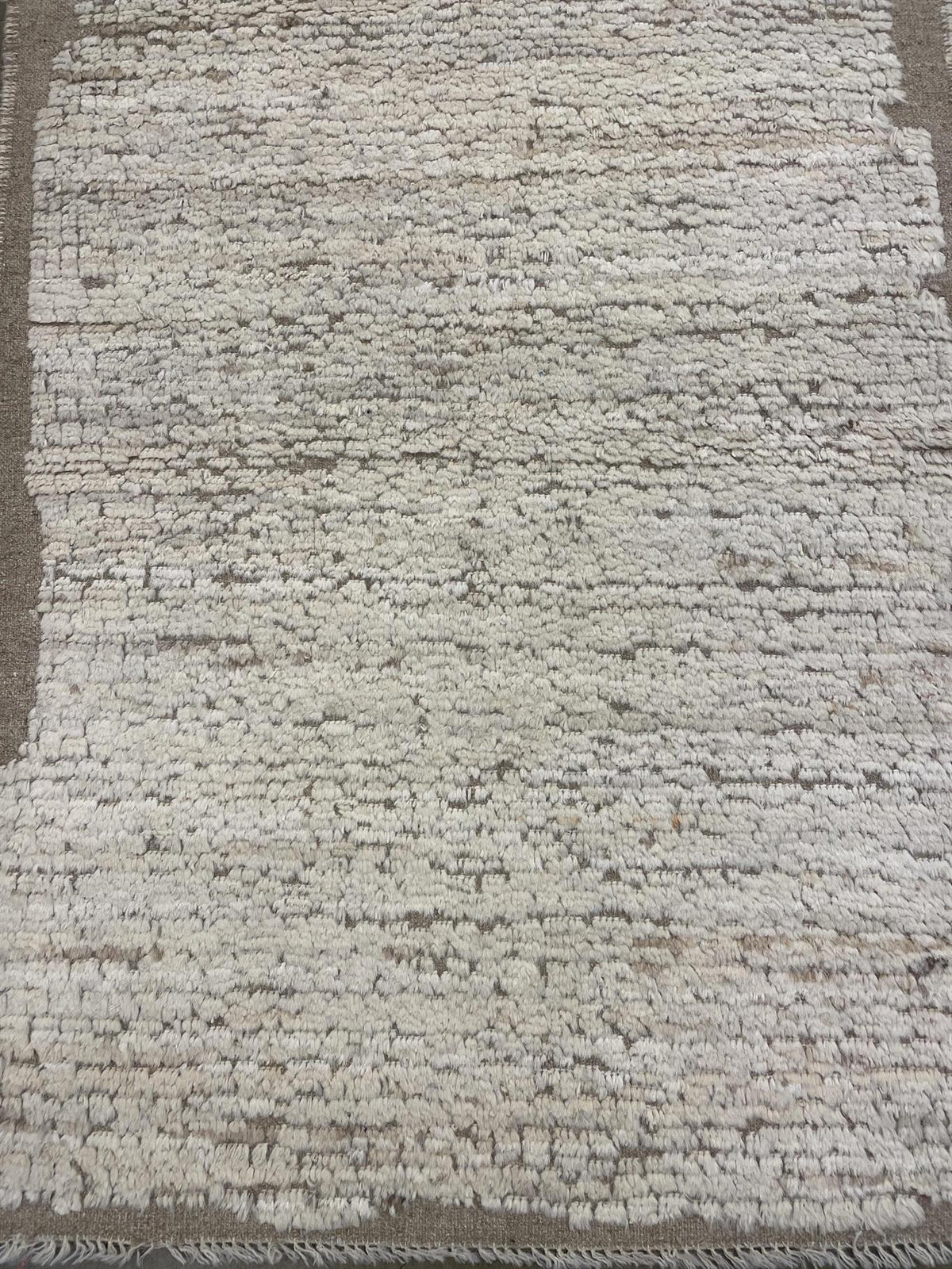 A close-up of a textured area rug with a distressed, hand-woven look in off-white and beige tones.Atlantica Organics curates antique and handmade rugs, Persian, Afghan, Tibetan, Pakistani, Turkish Oushak, Kilim, Khotan, tribal and contemporary textiles for luxury interiors, homes and real estate. Our collections connect timeless craftsmanship with interior design, furniture, fine art, architecture and modern living. Explore curated rugs, collectible textiles, natural materials, cultural heritage, sustainabl