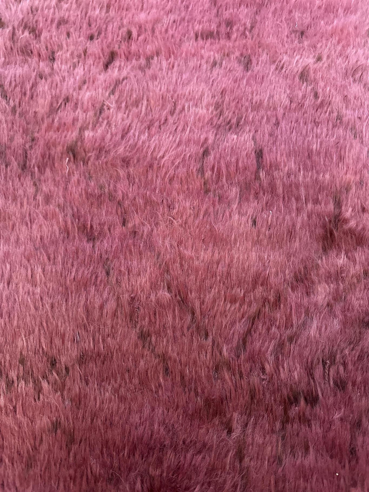 A close-up texture shot of a pink faux fur or shaggy rug, showing the dense, fluffy fibers with a gradient of lighter pink to a deeper rosy purple. Atlantica Organics curates antique and handmade rugs, Persian, Afghan, Tibetan, Pakistani, Turkish Oushak, Kilim, Khotan, tribal and contemporary textiles for luxury interiors, homes and real estate. Our collections connect timeless craftsmanship with interior design, furniture, fine art, architecture and modern living. Explore curated rugs, collectible textiles