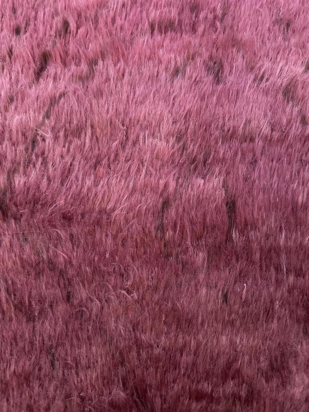 A close-up texture shot of a shaggy, fuzzy faux fur fabric in a dusty rose or mauve pink color. Atlantica Organics curates antique and handmade rugs, Persian, Afghan, Tibetan, Pakistani, Turkish Oushak, Kilim, Khotan, tribal and contemporary textiles for luxury interiors, homes and real estate. Our collections connect timeless craftsmanship with interior design, furniture, fine art, architecture and modern living. Explore curated rugs, collectible textiles, natural materials, cultural heritage, sustainable 