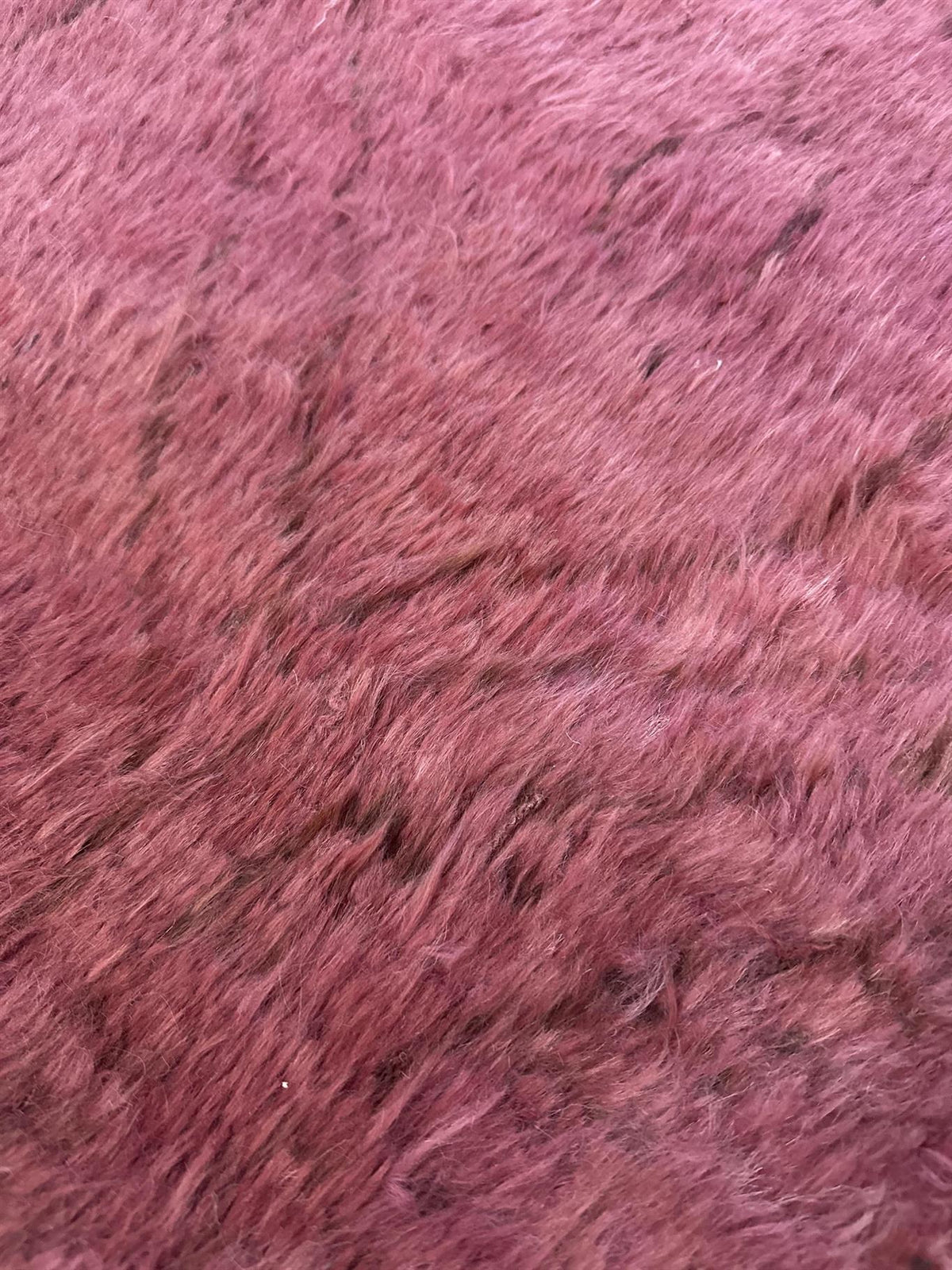 A close-up texture shot of a pink faux fur or shaggy fabric material. Atlantica Organics curates antique and handmade rugs, Persian, Afghan, Tibetan, Pakistani, Turkish Oushak, Kilim, Khotan, tribal and contemporary textiles for luxury interiors, homes and real estate. Our collections connect timeless craftsmanship with interior design, furniture, fine art, architecture and modern living. Explore curated rugs, collectible textiles, natural materials, cultural heritage, sustainable design and distinctive spa