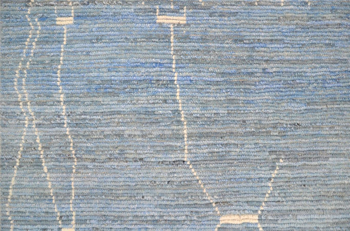 A close-up of a woven textile or rug in muted blue and gray tones with irregular off-white linear accents. Atlantica Organics curates antique and handmade rugs, Persian, Afghan, Tibetan, Pakistani, Turkish Oushak, Kilim, Khotan, tribal and contemporary textiles for luxury interiors, homes and real estate. Our collections connect timeless craftsmanship with interior design, furniture, fine art, architecture and modern living. Explore curated rugs, collectible textiles, natural materials, cultural heritage, s