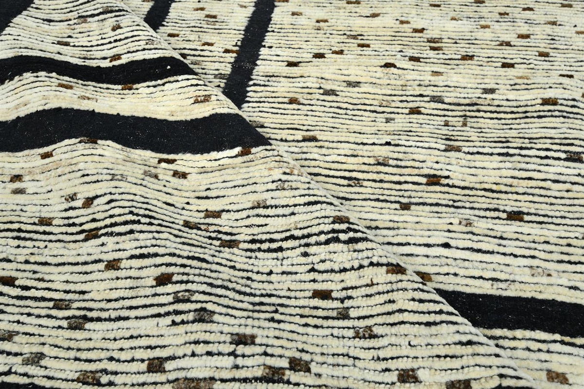 A close-up of a textured woven rug with a cream and black striped pattern and small brown dotted accents. Atlantica Organics curates antique and handmade rugs, Persian, Afghan, Tibetan, Pakistani, Turkish Oushak, Kilim, Khotan, tribal and contemporary textiles for luxury interiors, homes and real estate. Our collections connect timeless craftsmanship with interior design, furniture, fine art, architecture and modern living. Explore curated rugs, collectible textiles, natural materials, cultural heritage, su