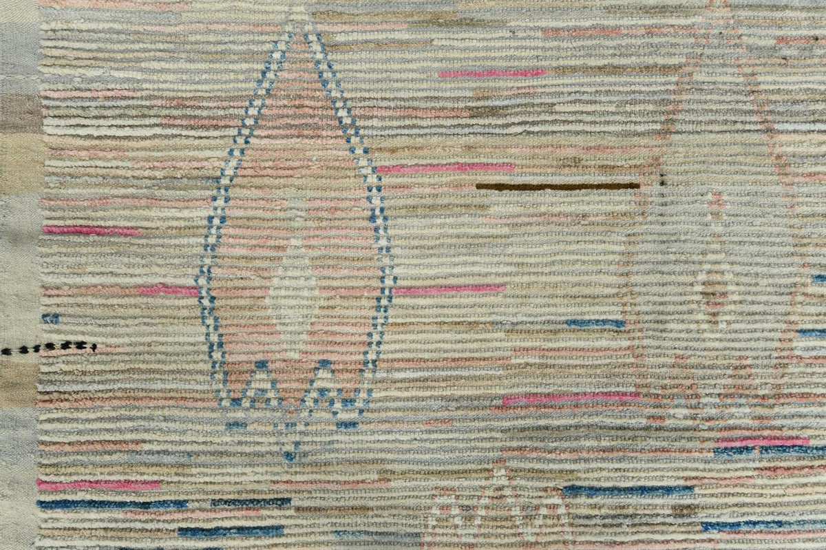 A close-up of a woven rug or textile with horizontal striped texture in beige, cream, pink, blue, and brown tones, featuring geometric and teardrop-like motifs. Atlantica Organics curates antique and handmade rugs, Persian, Afghan, Tibetan, Pakistani, Turkish Oushak, Kilim, Khotan, tribal and contemporary textiles for luxury interiors, homes and real estate. Our collections connect timeless craftsmanship with interior design, furniture, fine art, architecture and modern living. Explore curated rugs, collect