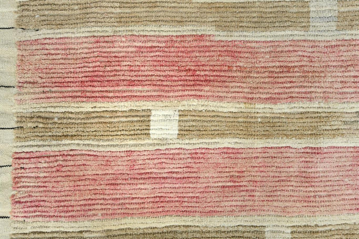 A close-up of a woven textile or rug showing horizontal bands of dusty pink, beige, and off-white with a textured, ribbed pattern. Atlantica Organics curates antique and handmade rugs, Persian, Afghan, Tibetan, Pakistani, Turkish Oushak, Kilim, Khotan, tribal and contemporary textiles for luxury interiors, homes and real estate. Our collections connect timeless craftsmanship with interior design, furniture, fine art, architecture and modern living. Explore curated rugs, collectible textiles, natural materia