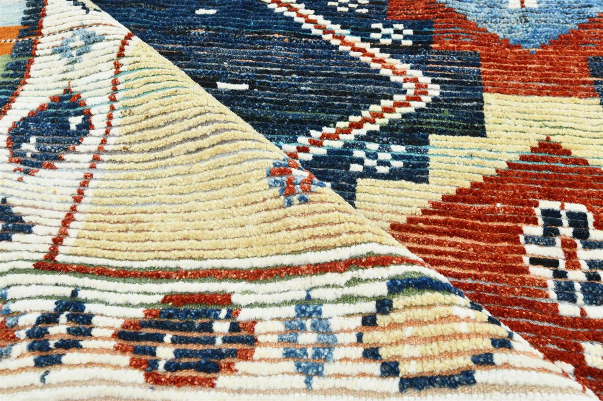 Close-up of a woven rug showing geometric patterns in cream, navy blue, rust red, and orange. Atlantica Organics curates antique and handmade rugs, Persian, Afghan, Tibetan, Pakistani, Turkish Oushak, Kilim, Khotan, tribal and contemporary textiles for luxury interiors, homes and real estate. Our collections connect timeless craftsmanship with interior design, furniture, fine art, architecture and modern living. Explore curated rugs, collectible textiles, natural materials, cultural heritage, sustainable de