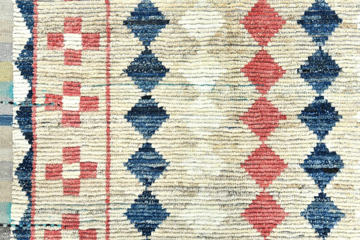 A close-up of a woven textile or rug pattern with vertical bands of cream, navy blue, and coral red geometric motifs, including diamond and cross shapes. Atlantica Organics curates antique and handmade rugs, Persian, Afghan, Tibetan, Pakistani, Turkish Oushak, Kilim, Khotan, tribal and contemporary textiles for luxury interiors, homes and real estate. Our collections connect timeless craftsmanship with interior design, furniture, fine art, architecture and modern living. Explore curated rugs, collectible te