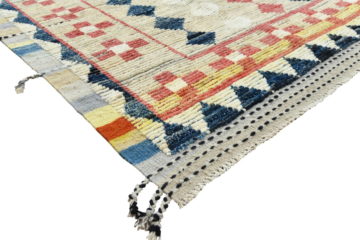 A close-up of a woven area rug with a geometric pattern in cream, navy blue, red, yellow, and light blue, featuring black fringe tassels on a white background.Atlantica Organics curates antique and handmade rugs, Persian, Afghan, Tibetan, Pakistani, Turkish Oushak, Kilim, Khotan, tribal and contemporary textiles for luxury interiors, homes and real estate. Our collections connect timeless craftsmanship with interior design, furniture, fine art, architecture and modern living. Explore curated rugs, collectib