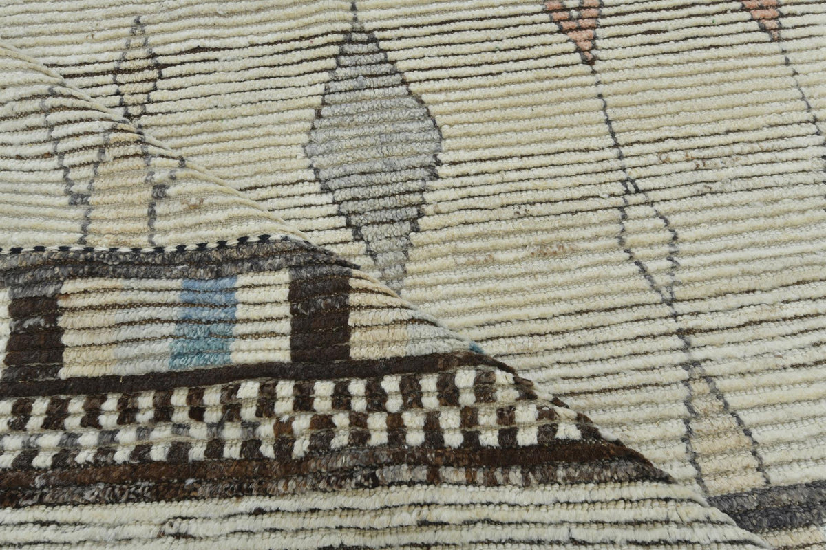 Close-up of a woven rug or textile with a geometric pattern in beige, brown, gray, and small muted blue accents. Atlantica Organics curates antique and handmade rugs, Persian, Afghan, Tibetan, Pakistani, Turkish Oushak, Kilim, Khotan, tribal and contemporary textiles for luxury interiors, homes and real estate. Our collections connect timeless craftsmanship with interior design, furniture, fine art, architecture and modern living. Explore curated rugs, collectible textiles, natural materials, cultural herit