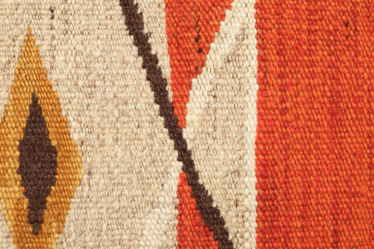 Close-up of a woven textile pattern with a cream base, a rust orange field, and dark brown geometric accents.Atlantica Organics curates antique and handmade rugs, Persian, Afghan, Tibetan, Pakistani, Turkish Oushak, Kilim, Khotan, tribal and contemporary textiles for luxury interiors, homes and real estate. Our collections connect timeless craftsmanship with interior design, furniture, fine art, architecture and modern living. Explore curated rugs, collectible textiles, natural materials, cultural heritage,