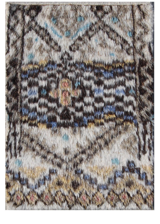 A close-up of a textured area rug with a distressed tribal pattern in beige, brown, black, blue, and yellow. Atlantica Organics curates antique and handmade rugs, Persian, Afghan, Tibetan, Pakistani, Turkish Oushak, Kilim, Khotan, tribal and contemporary textiles for luxury interiors, homes and real estate. Our collections connect timeless craftsmanship with interior design, furniture, fine art, architecture and modern living. Explore curated rugs, collectible textiles, natural materials, cultural heritage,